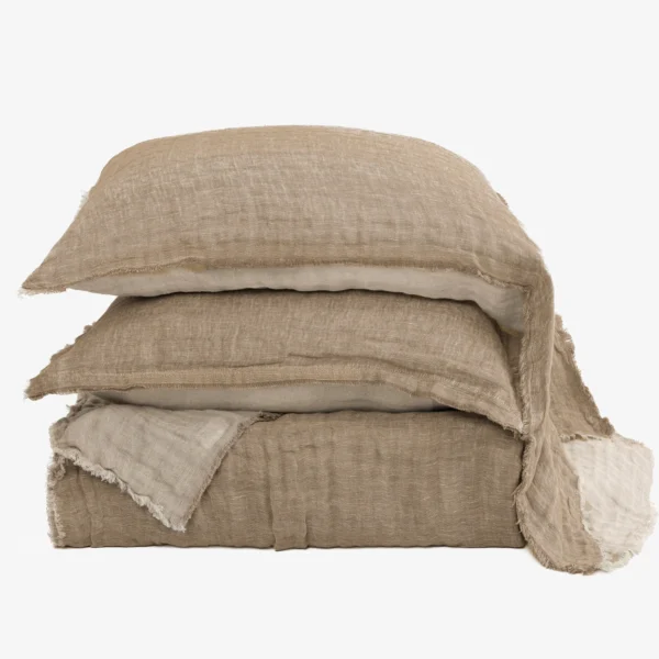 Stack of beige linen cushions with frayed edges against a white background