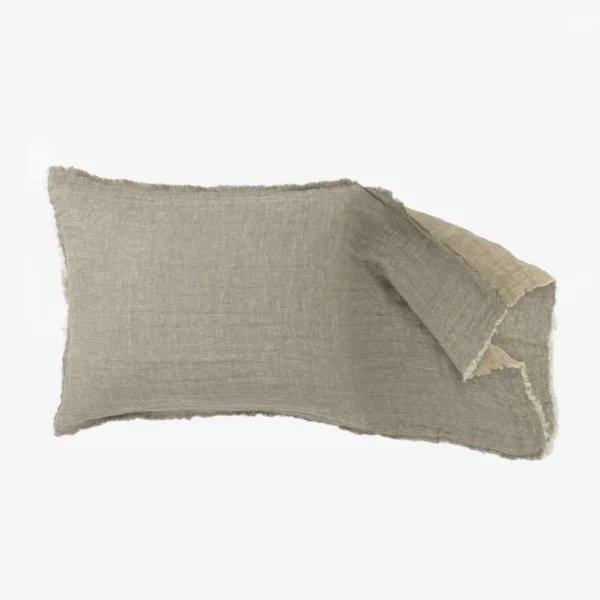 Beige linen pillow with frayed edges resting on a light background close up of fabric weave and texture