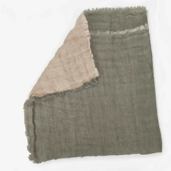 Gray woven fabric with frayed edges and a pale pink scarf draped over it shown in close up