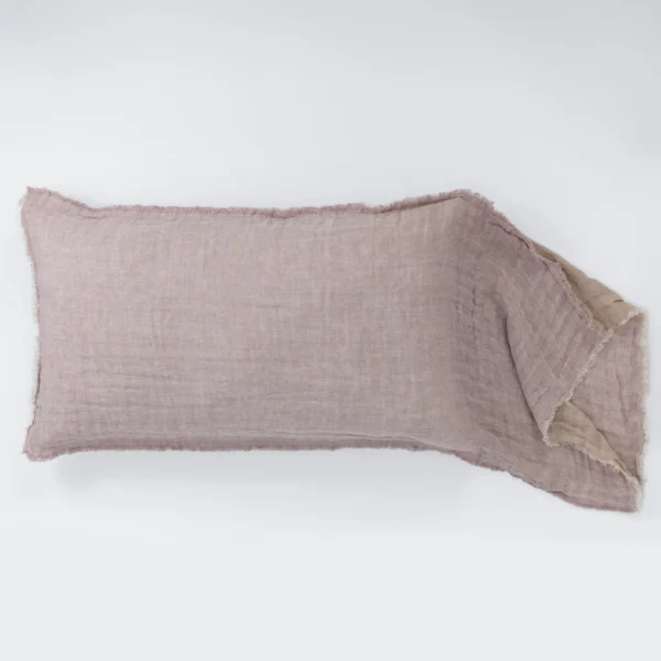 Light pink linen fabric with frayed edges laid across a white surface