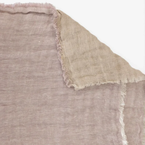 Close up of beige burlap fabric with a frayed edge and visible woven texture