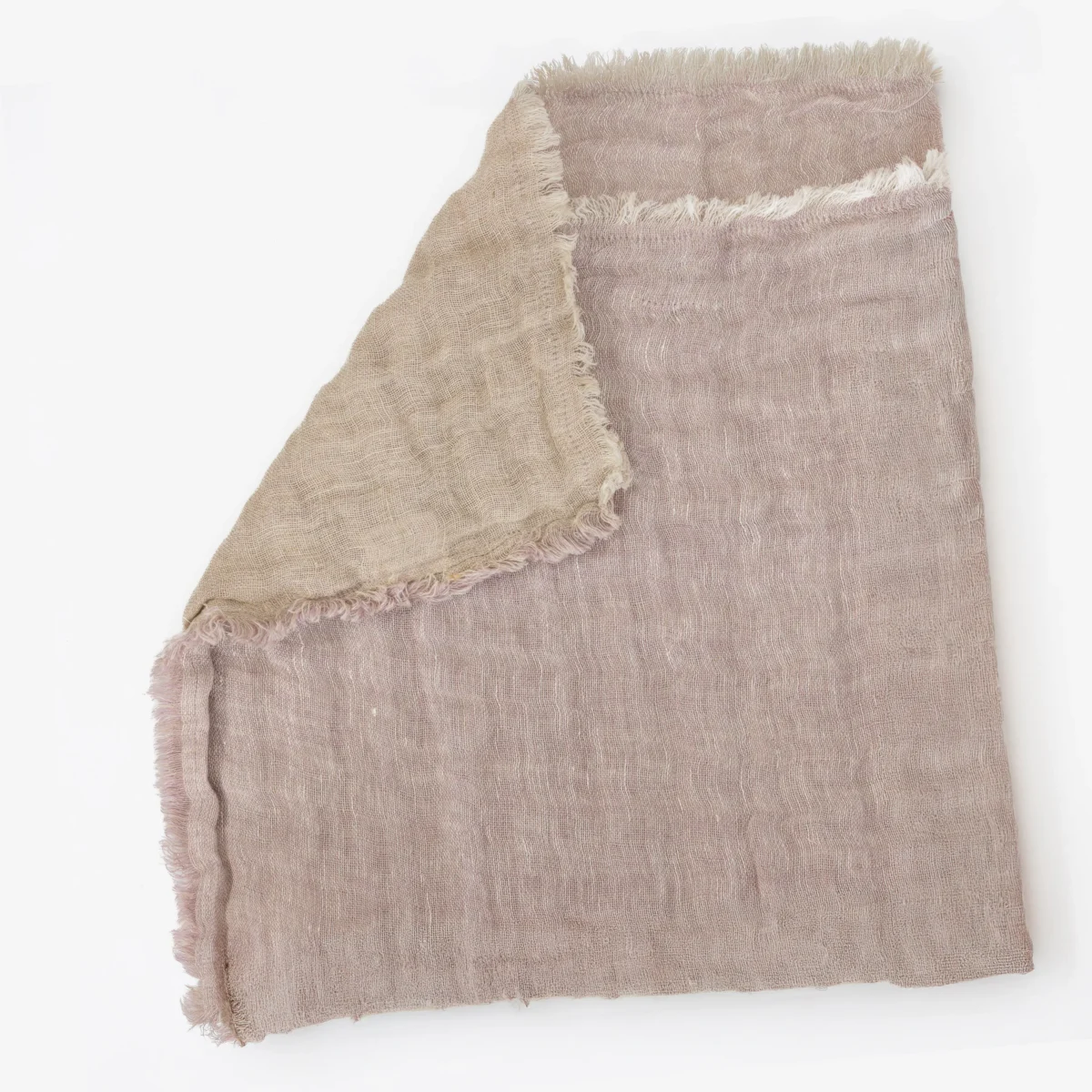 Close up of a light pink beige woven fabric with frayed edges folded on a white background by the corner