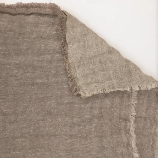 Close-up of beige burlap fabric with frayed seam running diagonally across the frame.