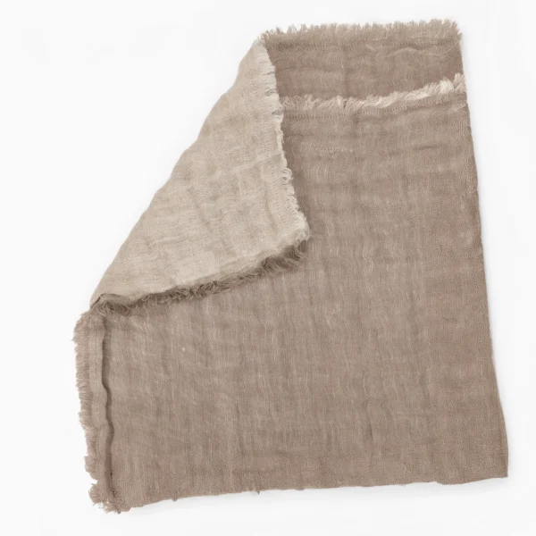 Beige woven scarf with frayed edges folded on a white background