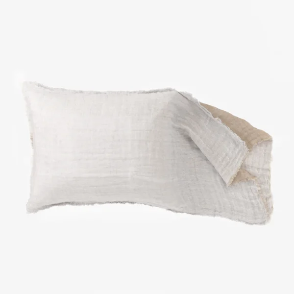Close up of light gray linen fabric with frayed edges laid in layered folds on a white background