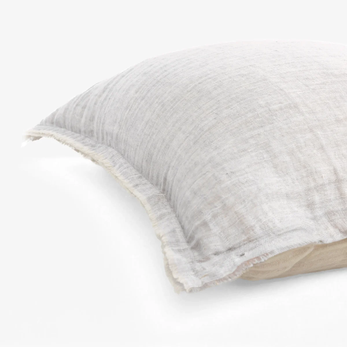 Close up of a light gray denim pillow with visible stitching on a white surface