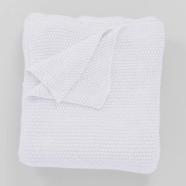 Folded white towels stacked neatly on a light gray background or surface