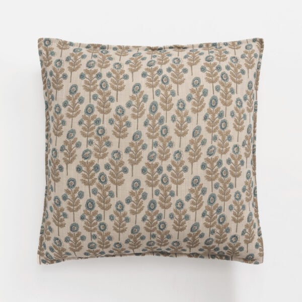 Decorative beige pillow with a blue and brown floral pattern on a white surface.