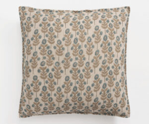Decorative beige pillow with a blue and brown floral pattern on a white surface