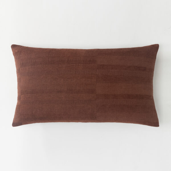 Brown textured cushionpillow against a plain white background cropped to show the top edge and part of the pillow
