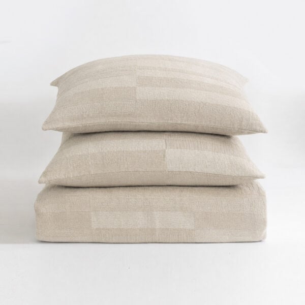 Stack of three beige textured throw pillows stacked on a white surface.](https://example.com)
