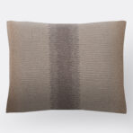 Close up of a textured beige brown woven fabric with a subtle striped pattern on a light background