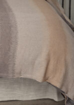 Close up of a soft beige woven fabric with subtle vertical stripe patterns draped over a surface