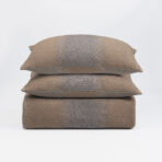 Three brown woven throw pillows stacked on a white background showing textured fabric and seam details down the center