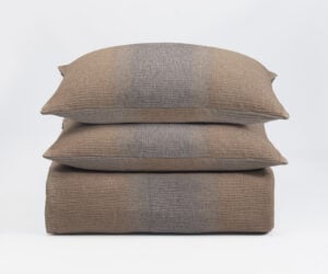 Three brown woven throw pillows stacked on a white background showing textured fabric and seam details down the center
