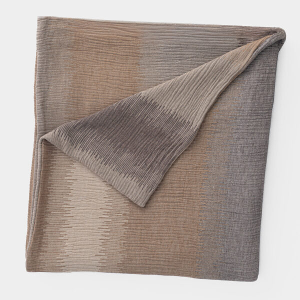 Close up of folded brown toned fabric with a subtle striped pattern on a white background or backdrop