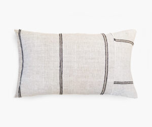 Cream textured throw pillow with black vertical stripes on a white background cropped to show the lower portion of the pillow edge