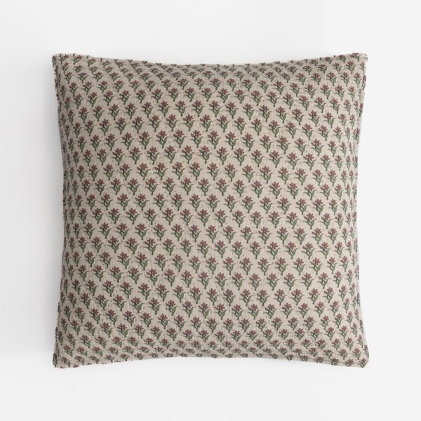 Patterned beige pillow with small red flowers and green stems repeated across the fabric pattern, viewed from above edge-on.