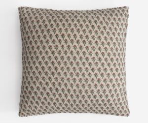 Patterned beige pillow with small red flowers and green stems repeated across the fabric pattern viewed from above edge on