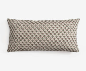 Close up of a decorative cushion with a small red and green floral pattern on beige fabric against a white background