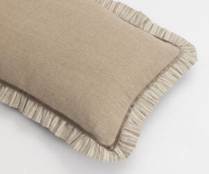 Two beige cushions with striped edges stacked on a white surface showing textured fabric and piping detail