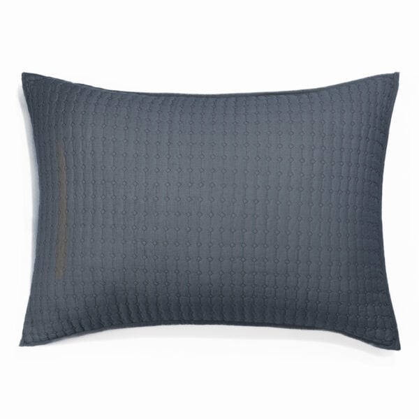 Dark blue textured pillow with a subtle hexagon pattern on a white background in a close up view