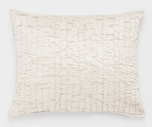 Cream colored quilted pillow with a grid of stitched squares on a white background