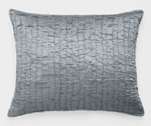 Close up of a large gray quilted pillow with a textured gridlike pattern on a light background