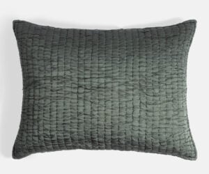 Dark green textured woven cushion with a raised grid pattern and soft edges against a light background