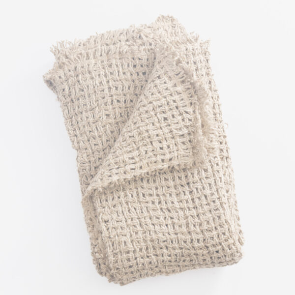 Beige chunky knit textile folded on a white surface close up of thick yarns