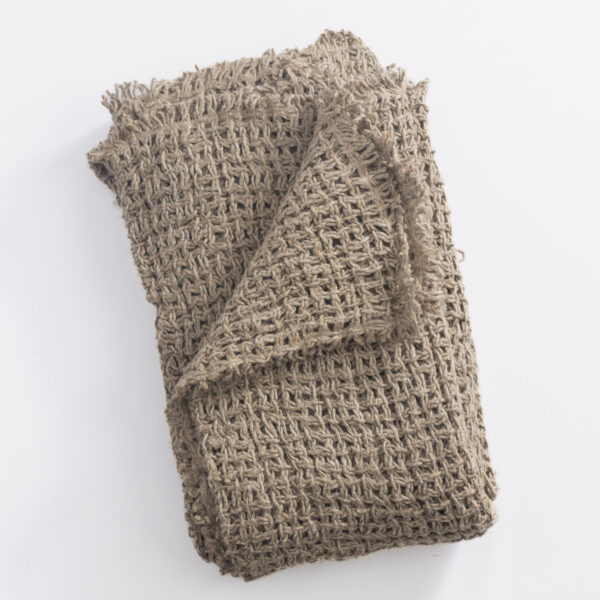 Close up of a folded chunky beige knit fabric with thick interwoven loops on a white background