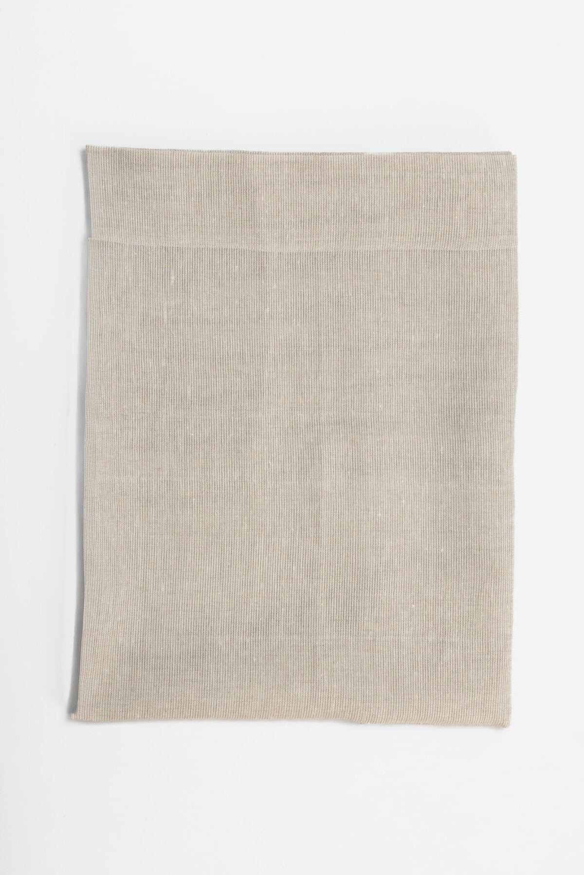 Folded beige fabric sample on a white background showing a soft knit texture and hem edge