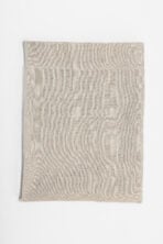 Folded beige fabric sample on a white background showing a soft knit texture and hem edge