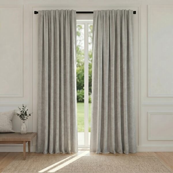 Light gray, floor-length curtains framing a glass door with a view of a green garden outside.