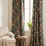 Sunlit living room corner with floral teal curtains a beige sofa and a small wooden table holding a book and cup by the window