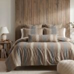 Cozy bedroom with a wooden paneled headboard neutral bed linens and matching pillows a lamp and small stack of books on a side table