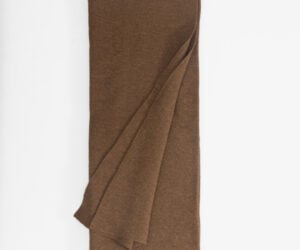 Brown knitted scarf folded lengthwise against a white background showing its texture and weave
