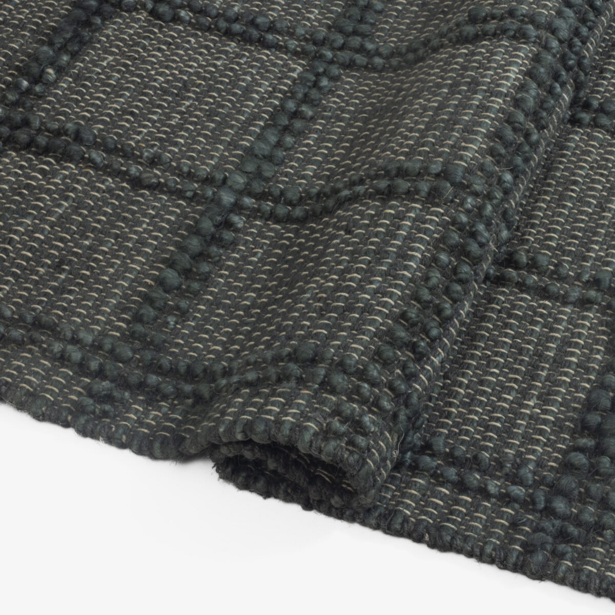 Close up of dark gray woven fabric with thick yarns and diagonal texture patterns showing a boucle like weave
