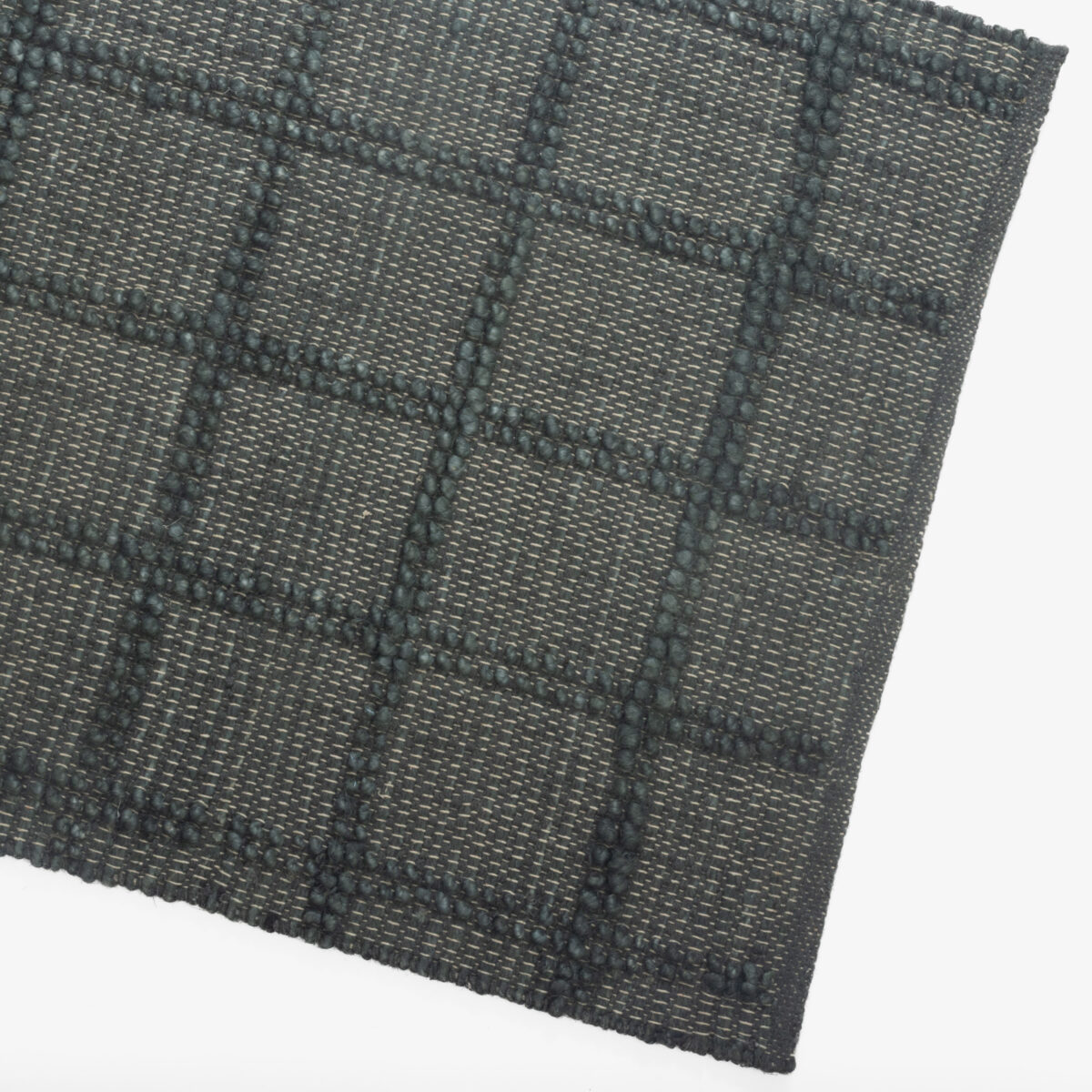 Close up of a dark textured woven fabric with a subtle diagonal weave and raised blue gray stitches forming geometric patterns