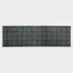 Close up of a dark gray woven rug with a square grid pattern laid on a light surface
