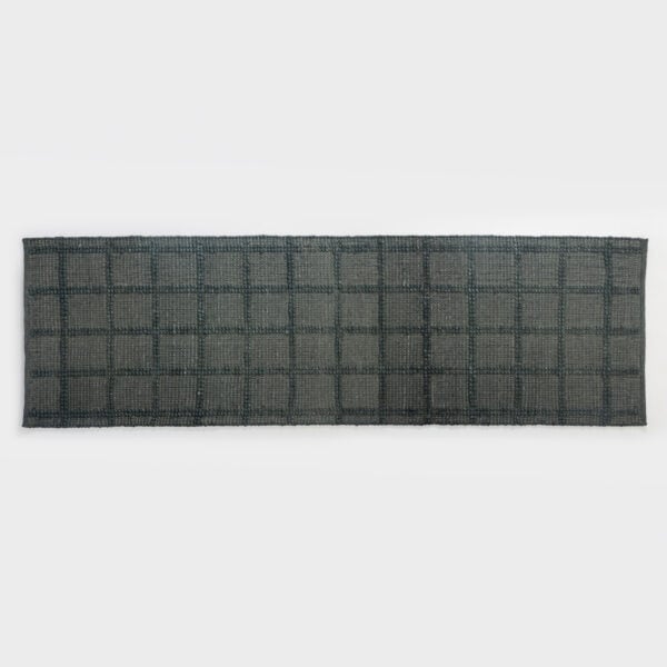 Close-up of a dark gray woven rug with a square grid pattern laid on a light surface.