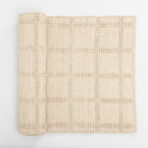 Beige woven textile close up with a dotted geometric pattern folded at the left edge on a white background