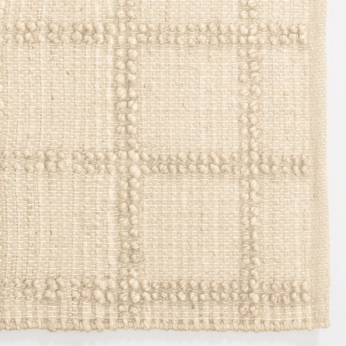 Close up of beige woven fabric with a grid like pattern and tufted knots
