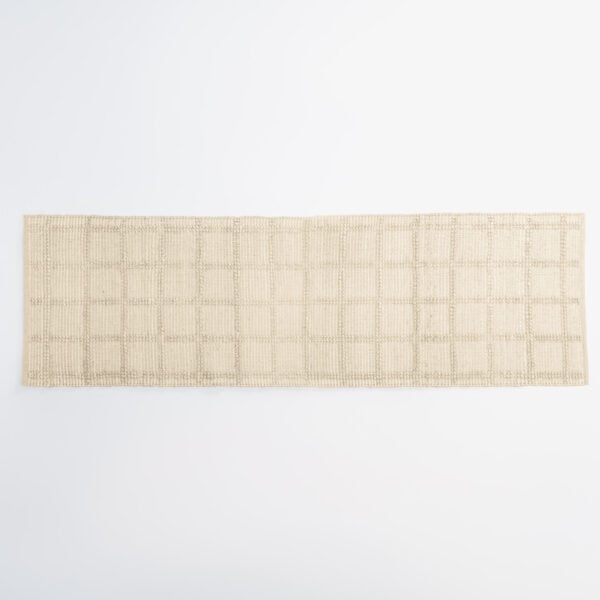 Beige woven rug along the bottom edge of a white background, showing its textured pattern.