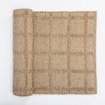 Close up of a beige woven fabric with raised beaded stripes and intricate texture on white background