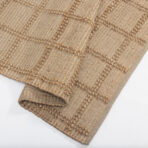 Close up of a beige woven rug with raised knot accents and a chunky texture