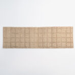 Bottom edge view of a beige woven rug with a textured pattern on a white background