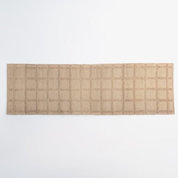 Bottom-edge view of a beige woven rug with a textured pattern on a white background.