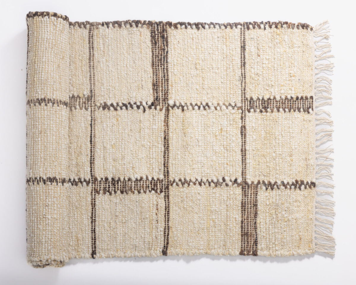 Beige woven rug with dark brown vertical stripes and fringe along the edge folded flat on a white background
