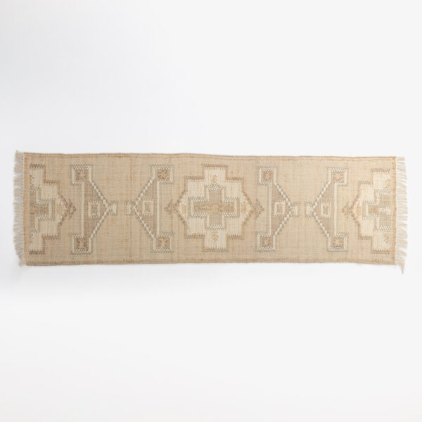 Beige woven rug with geometric square and diamond pattern and fringe along the bottom edge against a white background